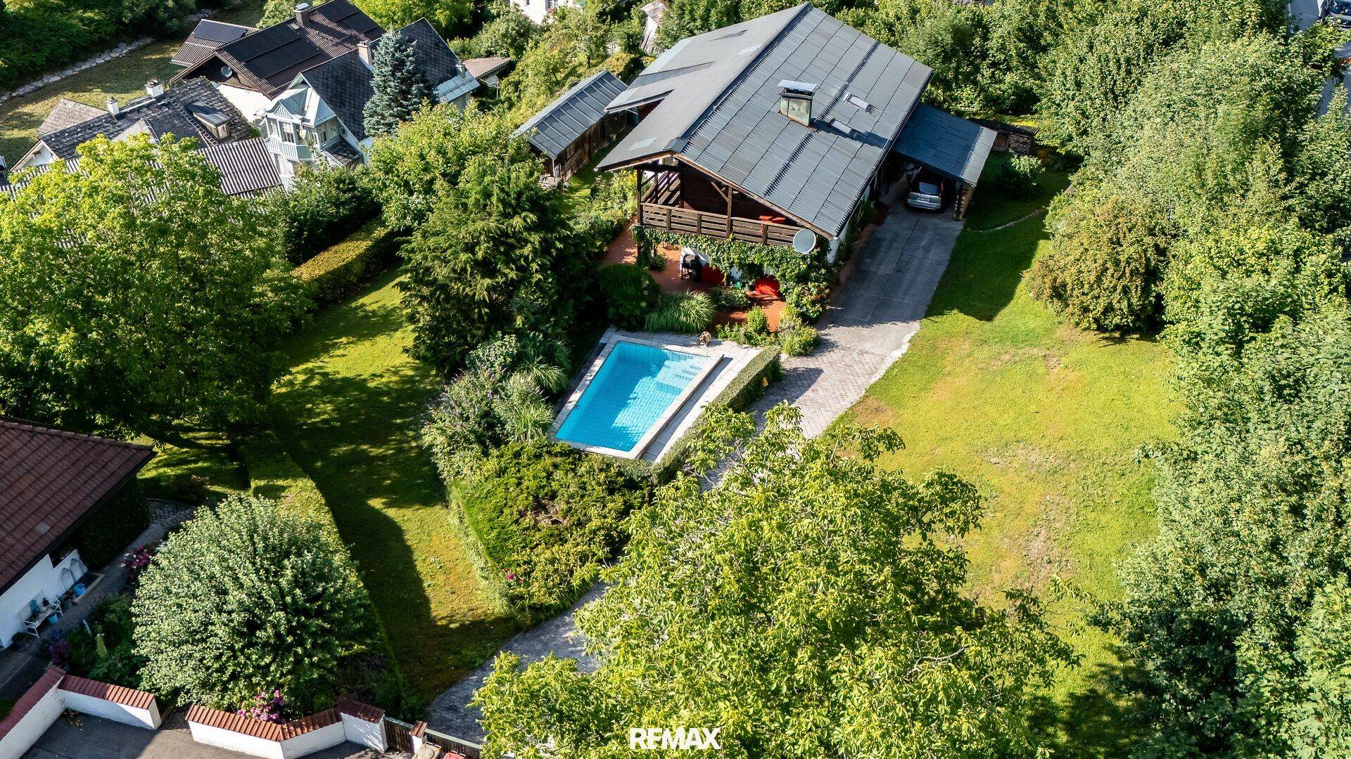 Luftaufnahme des Anwesens mit Haus, Pool und weitläufigem Garten in grüner Umgebung.