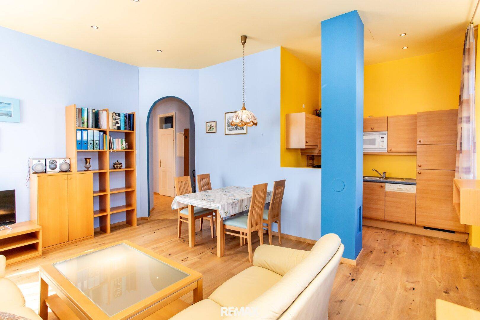 Offener Wohn-Essbereich mit integrierter Küche, Holzboden und farbenfroher Gestaltung.