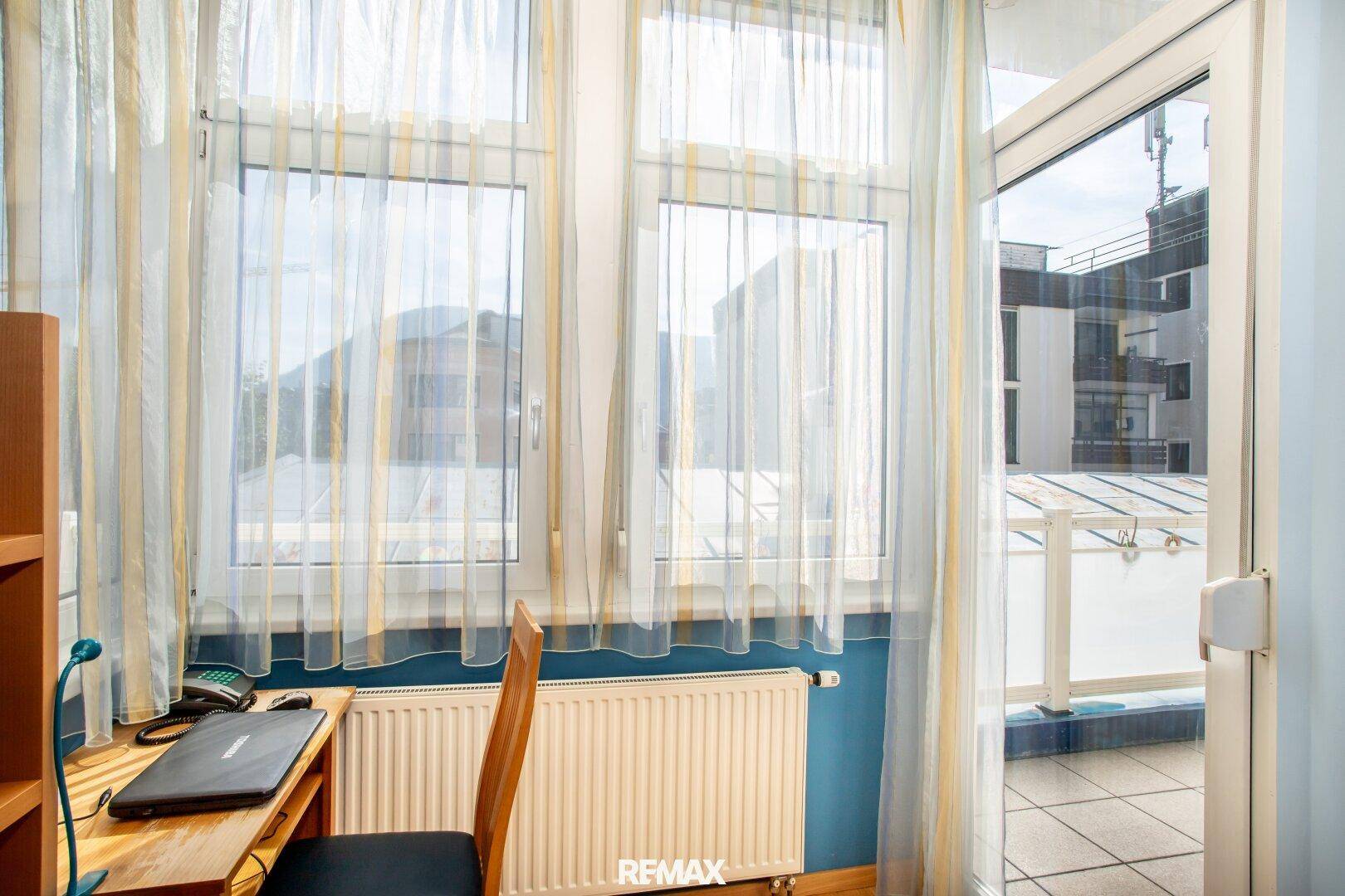 Fenster und Balkontür mit Blick auf die umliegenden Gebäude und den Himmel.