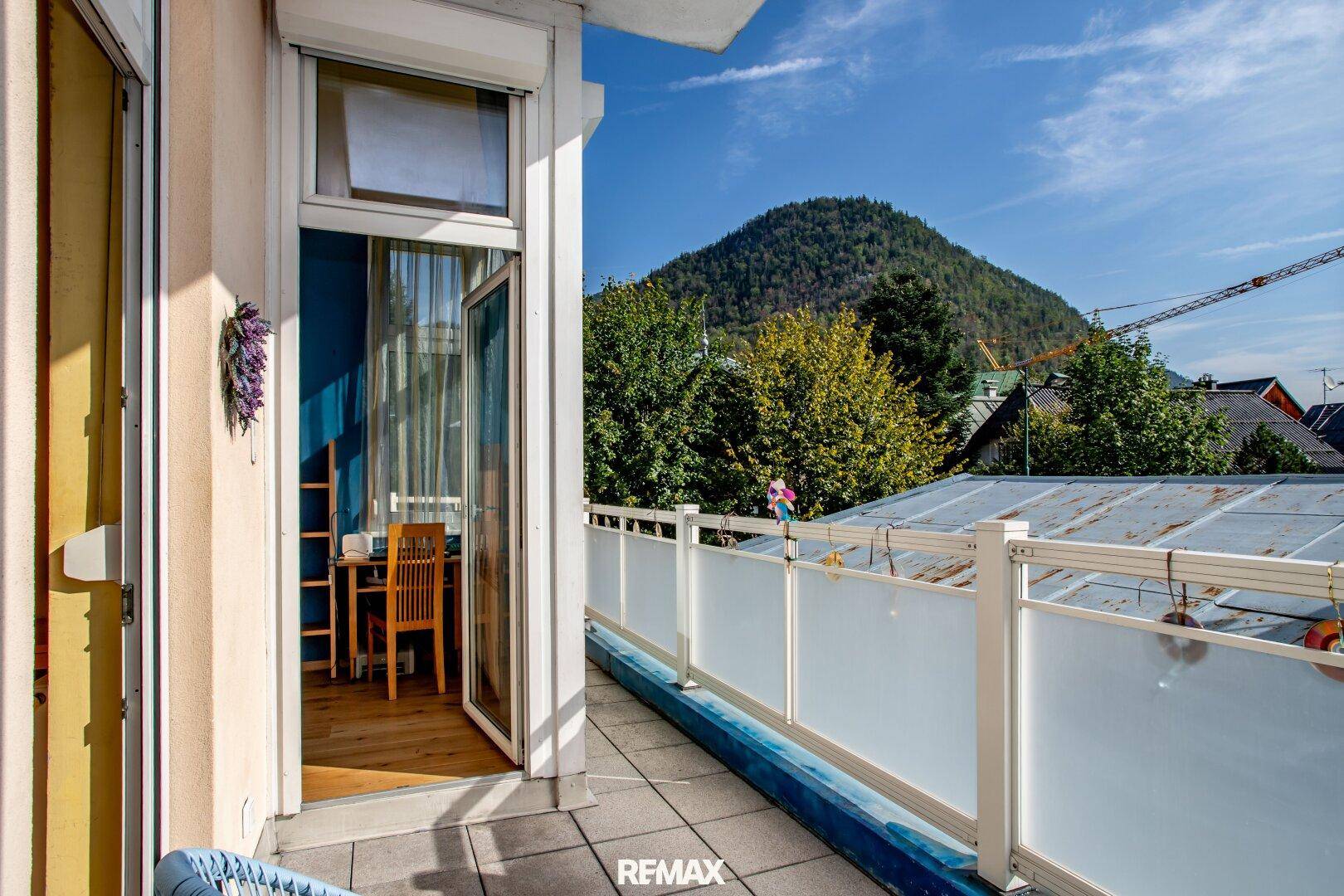 Großer Balkon mit Bergblick und Platz für Outdoor-Möbel unter blauem Himmel.