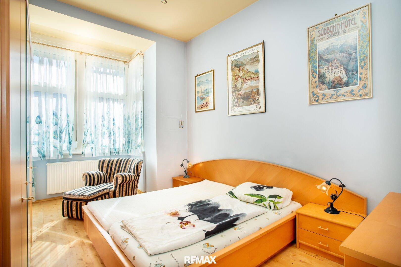 Schlafzimmer mit Doppelbett, Holzboden und großem Fenster für viel Tageslicht.