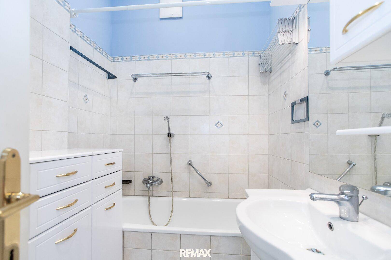Badezimmer mit Badewanne, Waschbecken und hellen Fliesen in klassischem Stil.