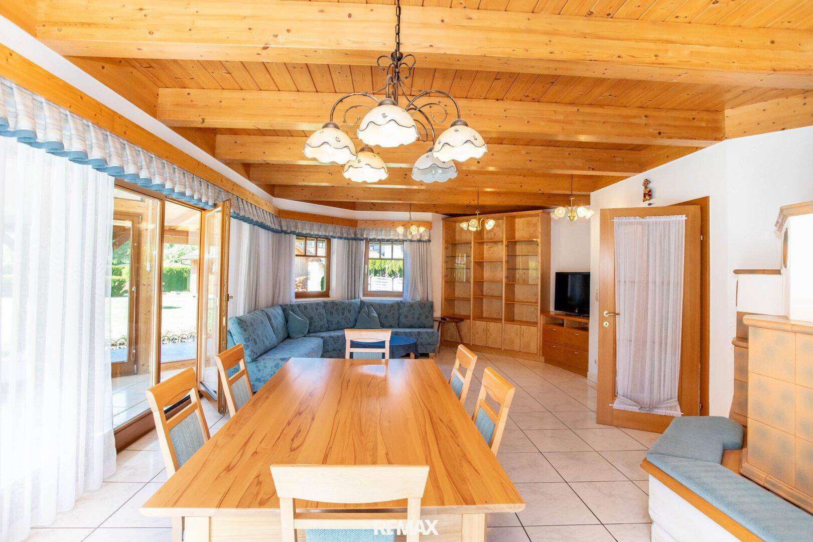 Gemütlicher Wohn-Essbereich mit Holzbalkendecke, großem Esstisch und Zugang zum Wintergarten.