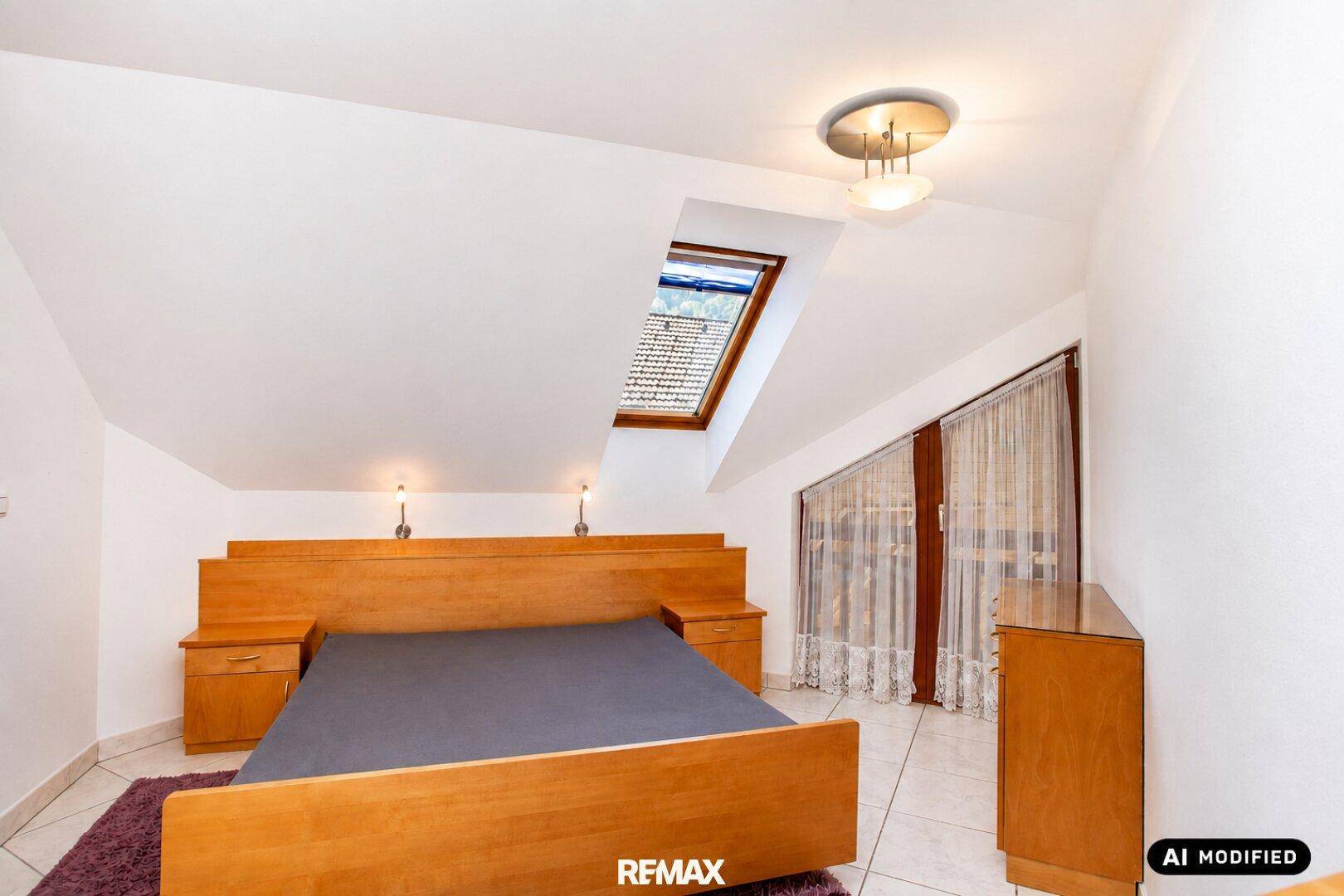 Schlafzimmer im Dachgeschoss mit Holzbett, Dachfenster und Zugang zu einem weiteren Raum.