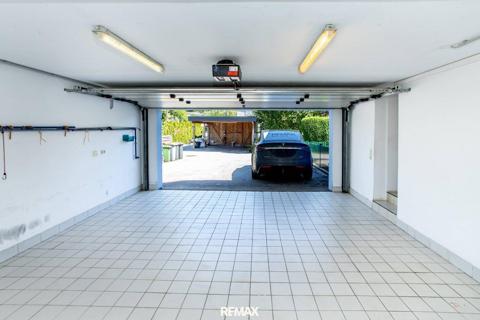 Geräumige Garage mit Fliesenboden und Blick auf die Einfahrt und den Außenbereich.
