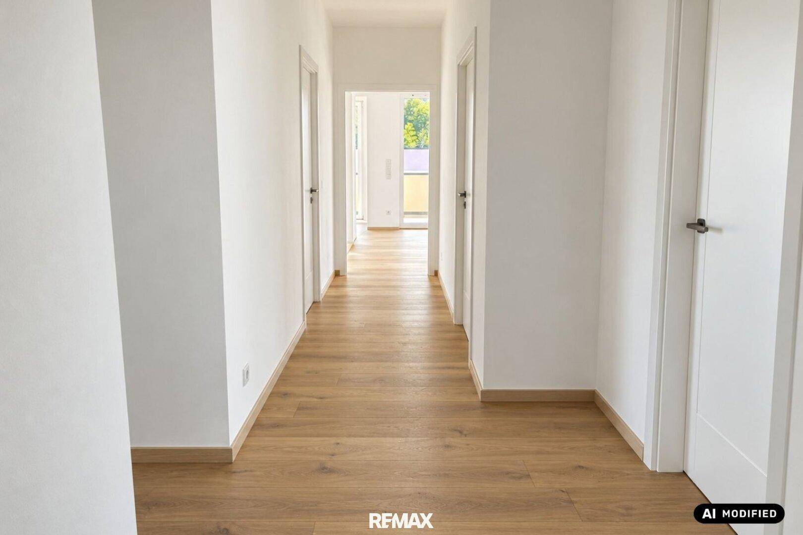 Heller Flur mit modernem Holzparkettboden und weißen Wänden, der zu weiteren Räumen führt.