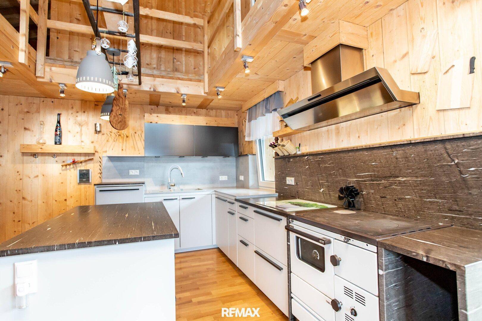 Geräumige Küche mit Holzvertäfelung, moderner Ausstattung und traditionellem Holzofen.