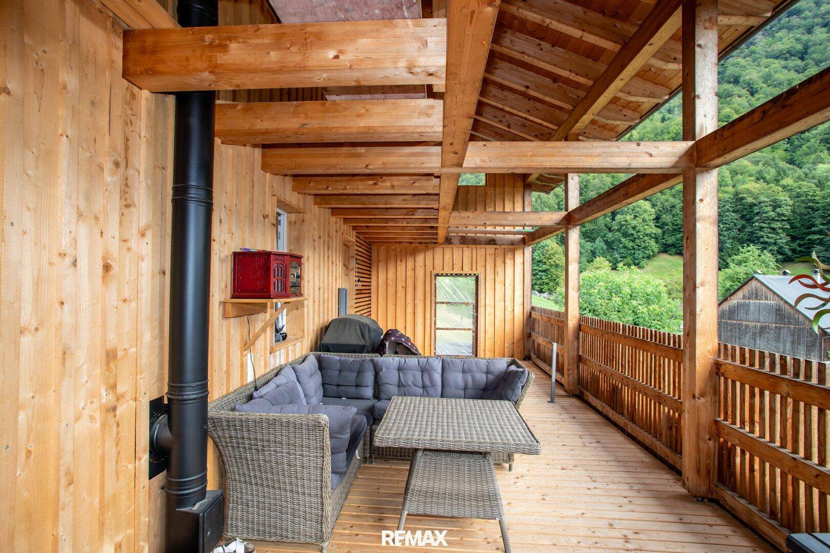 Gemütliche überdachte Terrasse mit Loungemöbeln und weitem Blick auf die umliegende Berglandschaft.