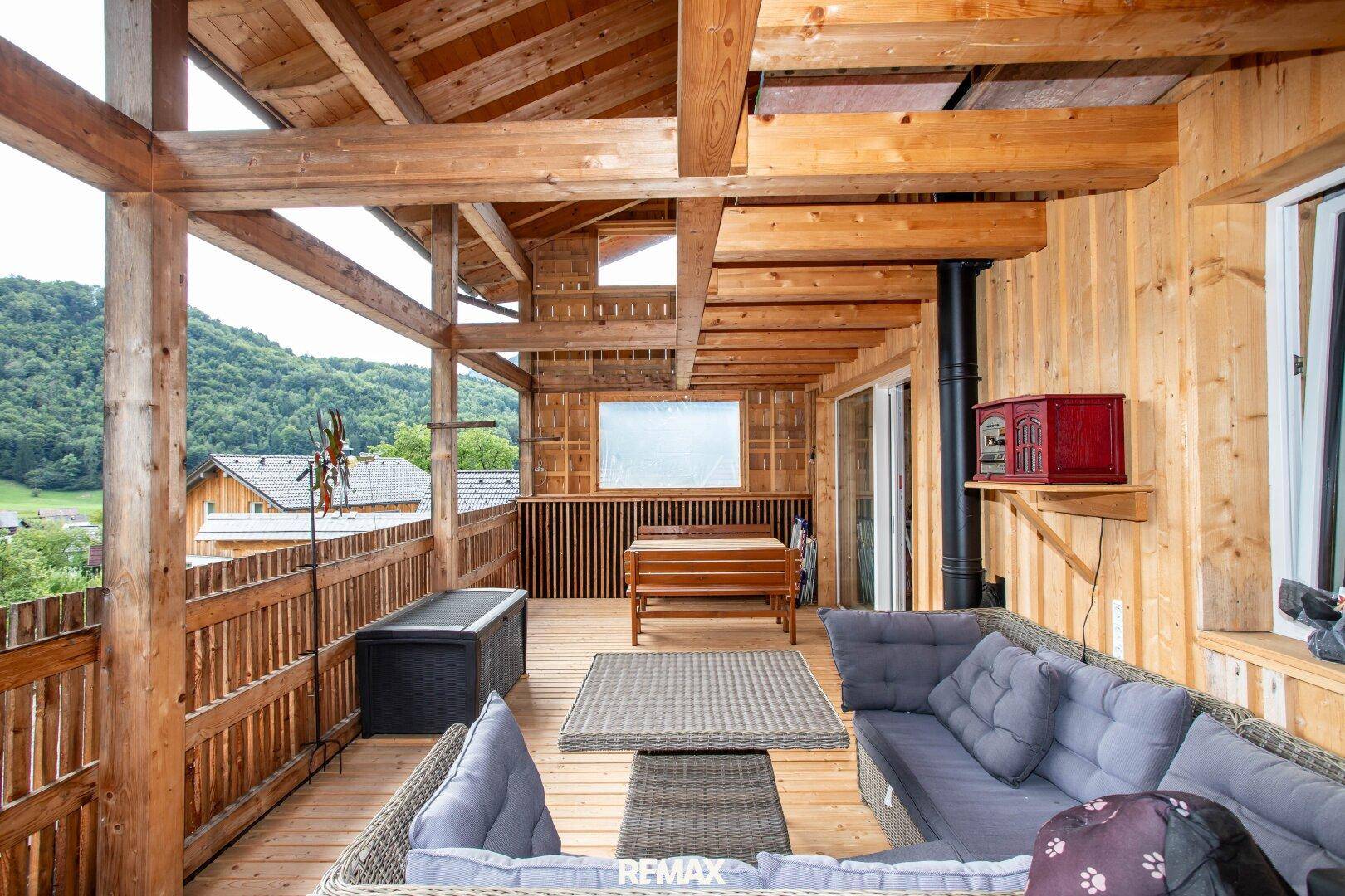 Große Holzterrasse mit bequemen Sitzgelegenheiten und einem weiten Blick über das Tal.