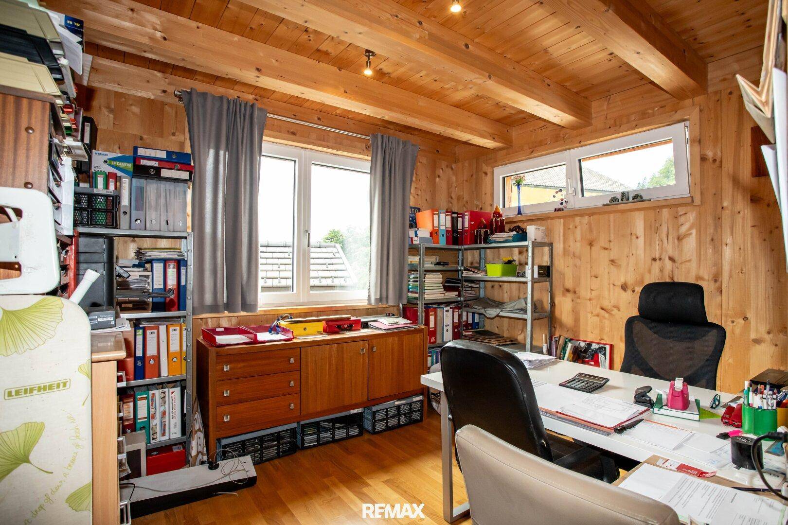 Funktionales Büro mit Holzvertäfelung, Schreibtisch und Regalen für eine produktive Arbeitsumgebung.