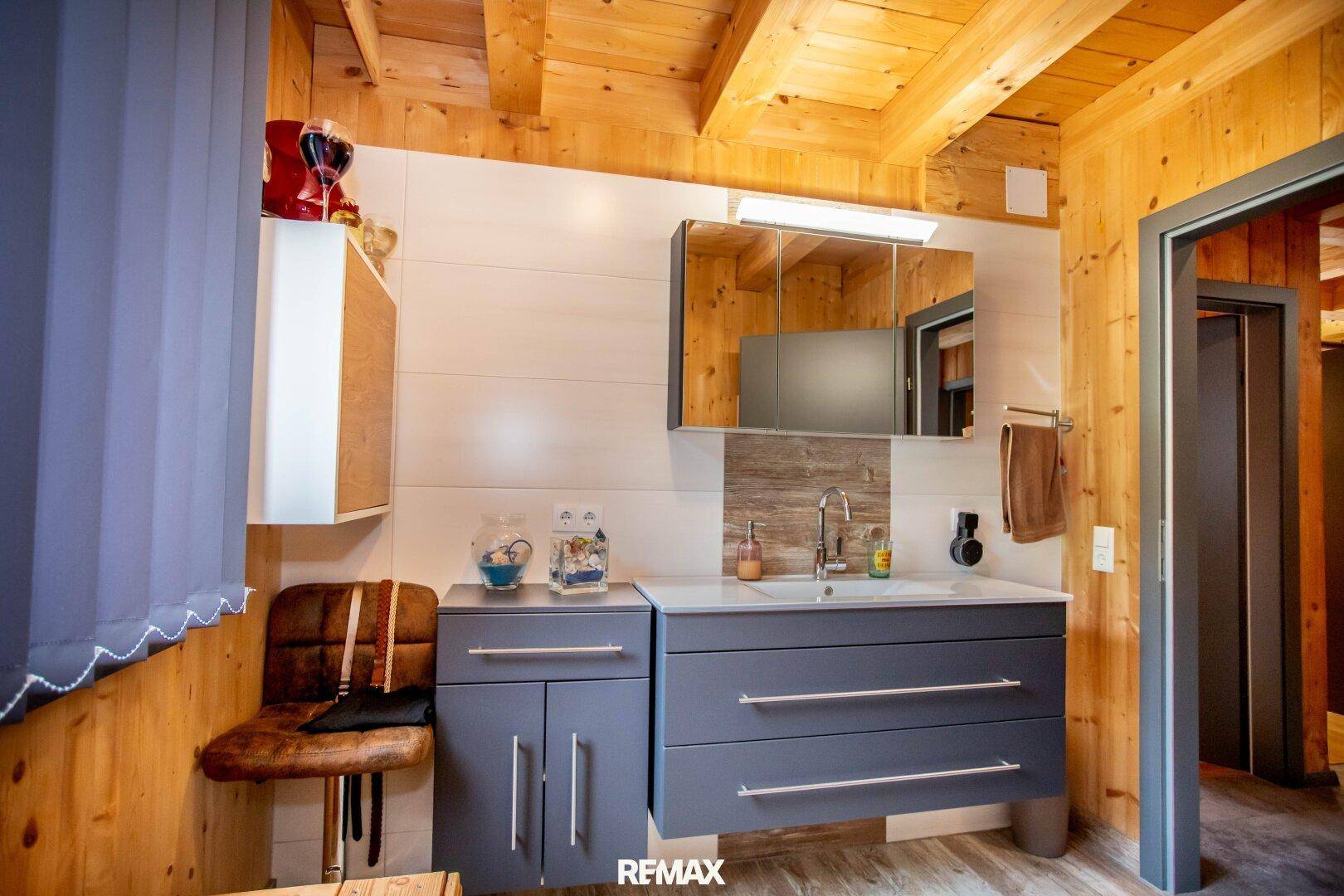 Modernes Badezimmer mit Holzvertäfelung, stilvollem Waschtisch und Spiegelschrank.