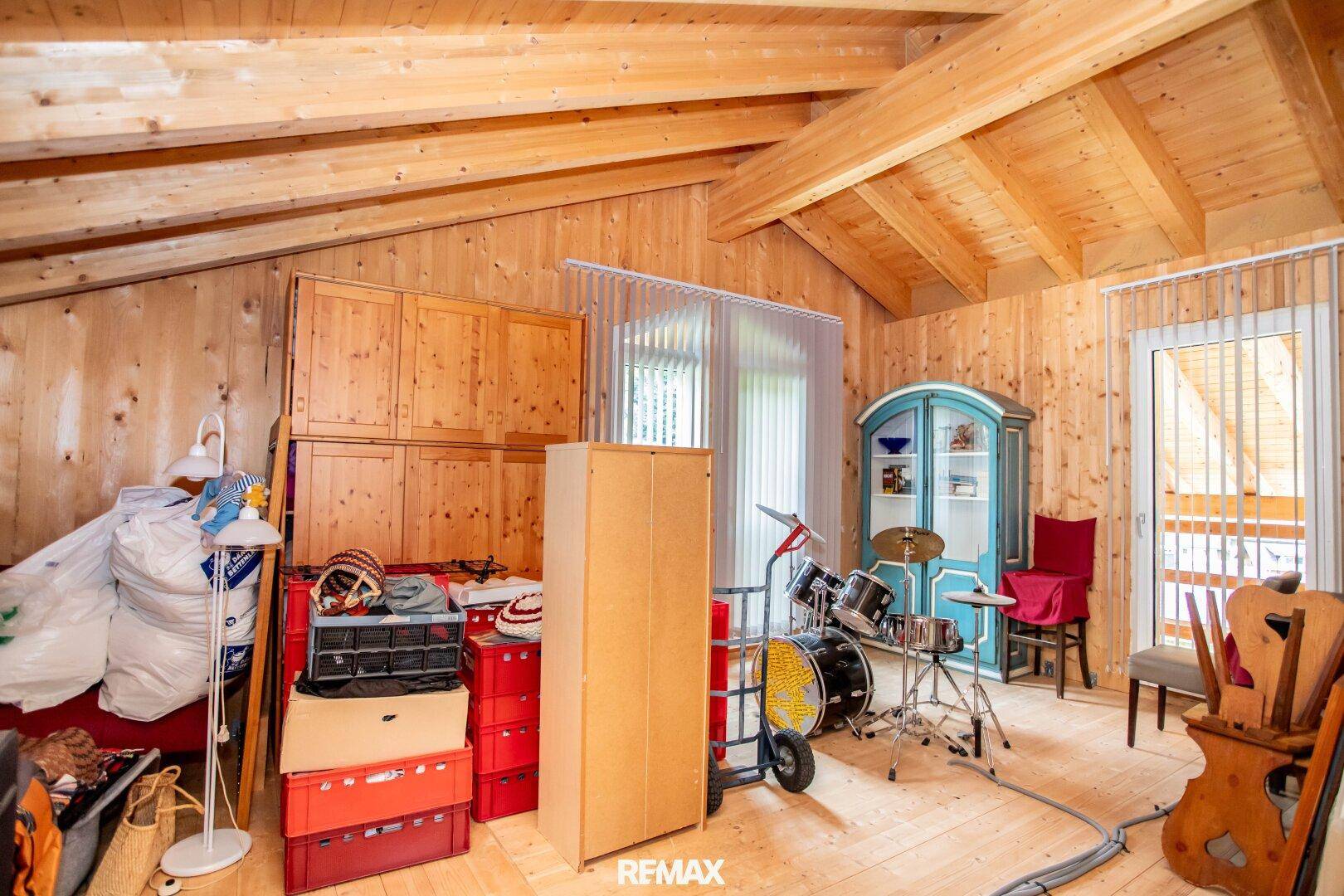 Dachzimmer mit Holzvertäfelung und schrägen Decken, derzeit als Abstellraum genutzt.