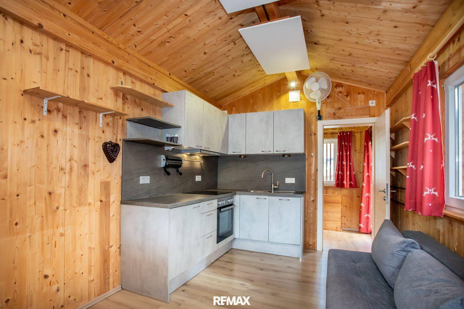 Kleine, funktionale Küche mit Holzverkleidung und Dachschräge, integriert in den Wohnbereich.