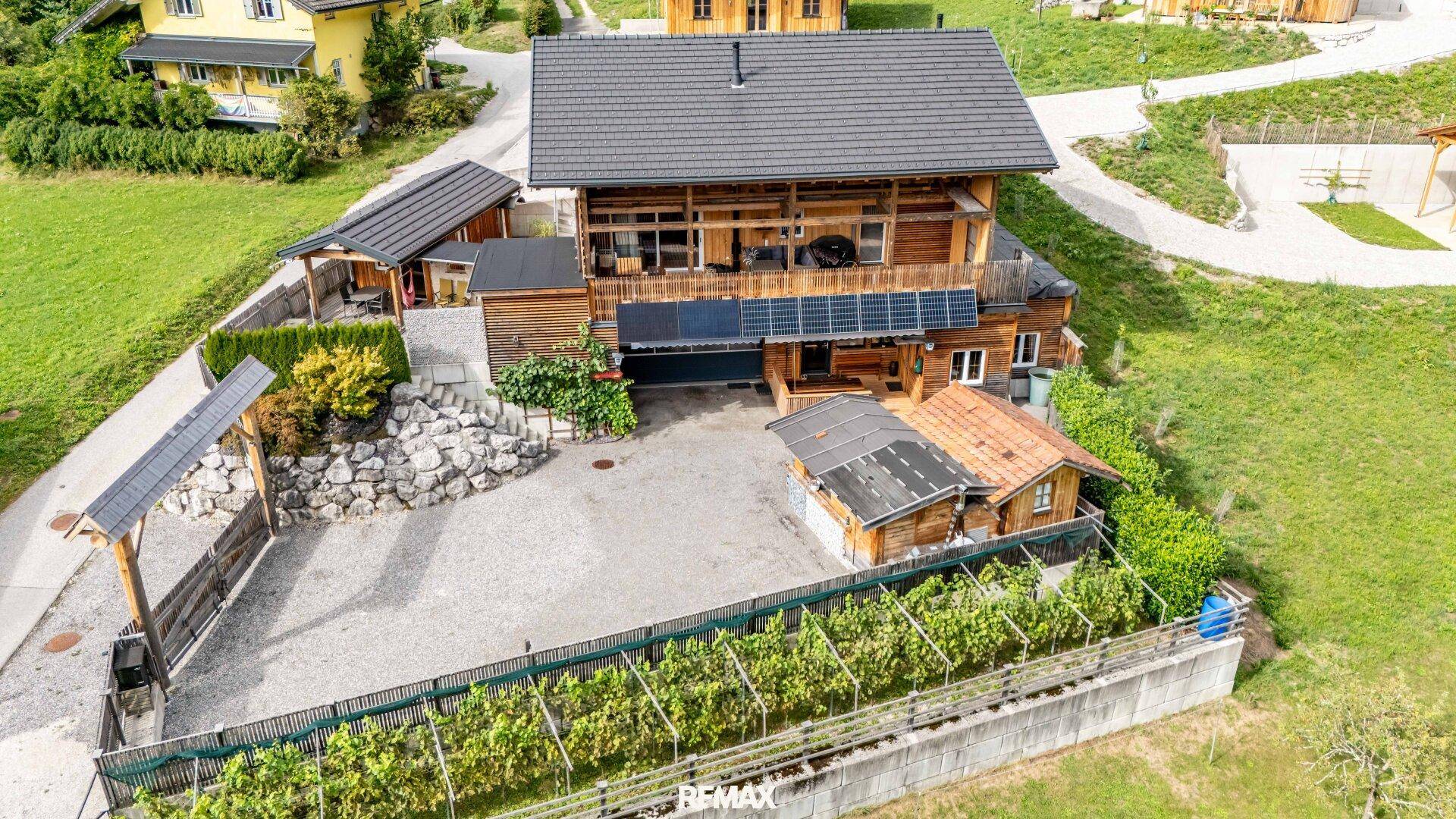 Luftaufnahme des Anwesens mit Haupthaus, Zufahrt und Photovoltaikanlage auf dem Dach.