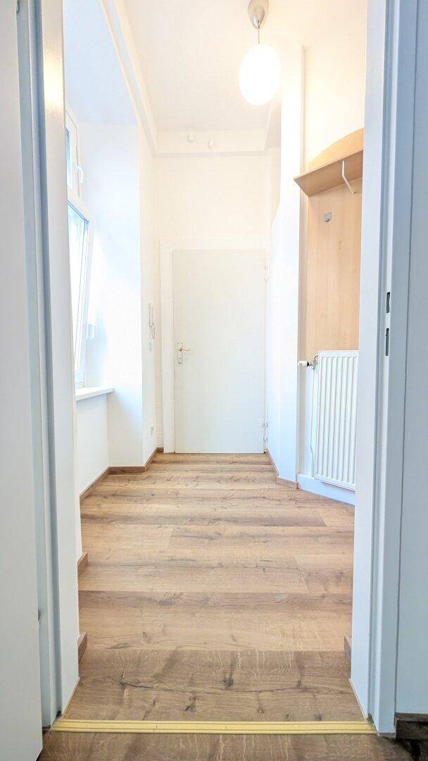 Heller Flur mit Laminatboden, weiß gestrichenen Wänden und einer Garderobennische.