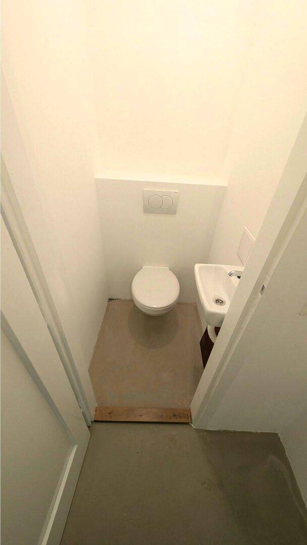 Kleine Gästetoilette mit wandhängendem WC und einem kompakten Waschbecken in hellem Design.