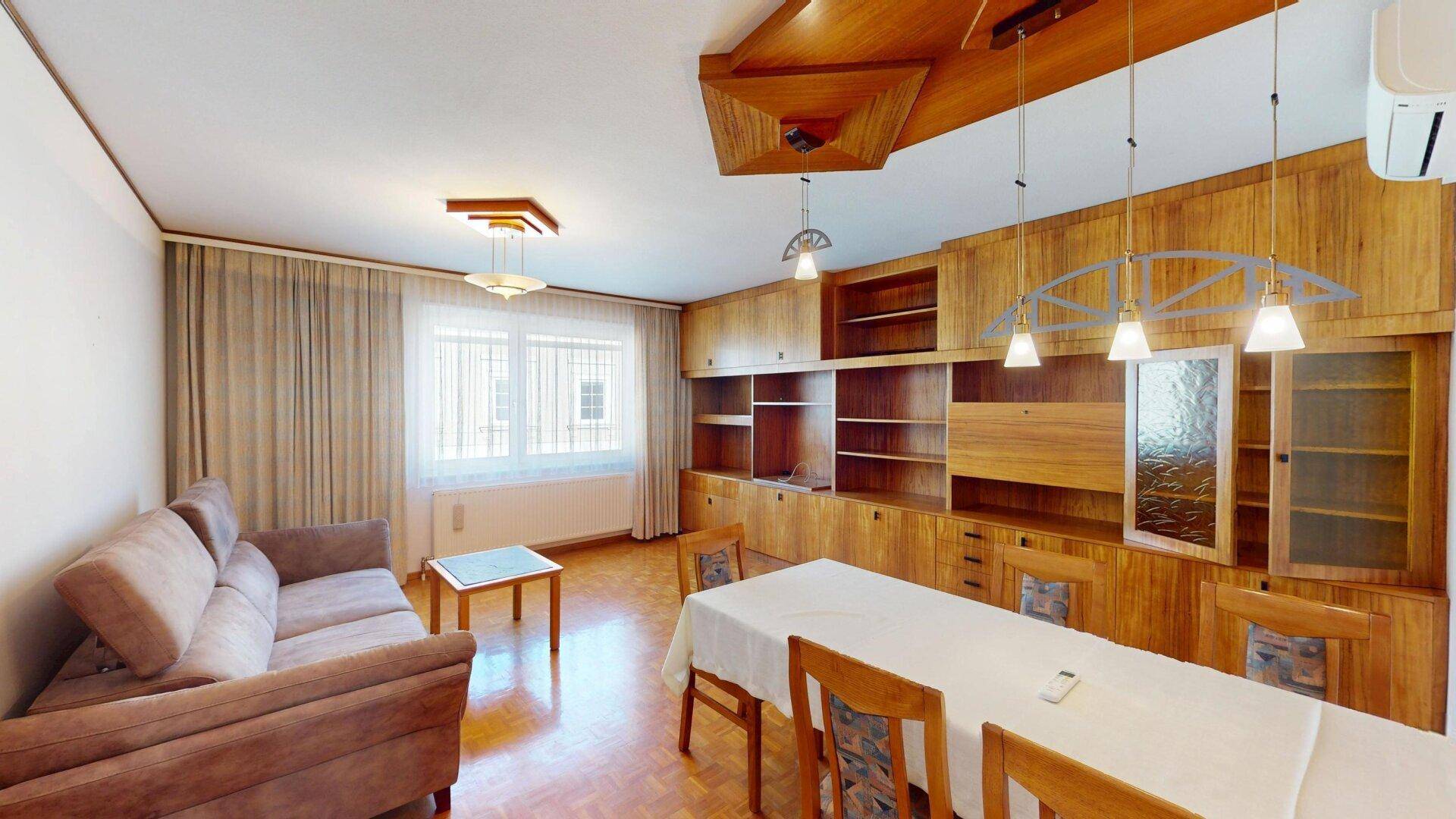 Geräumiger Wohn-Essbereich mit Holzvertäfelung, Parkettboden und gemütlicher Sitzecke.