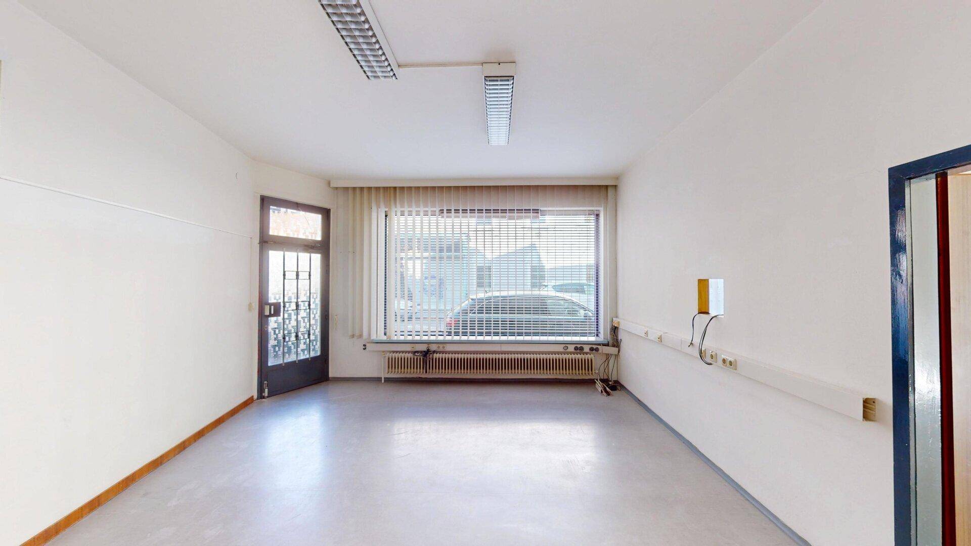 Heller Büroraum mit großem Fenster zur Straße und separatem Eingang.