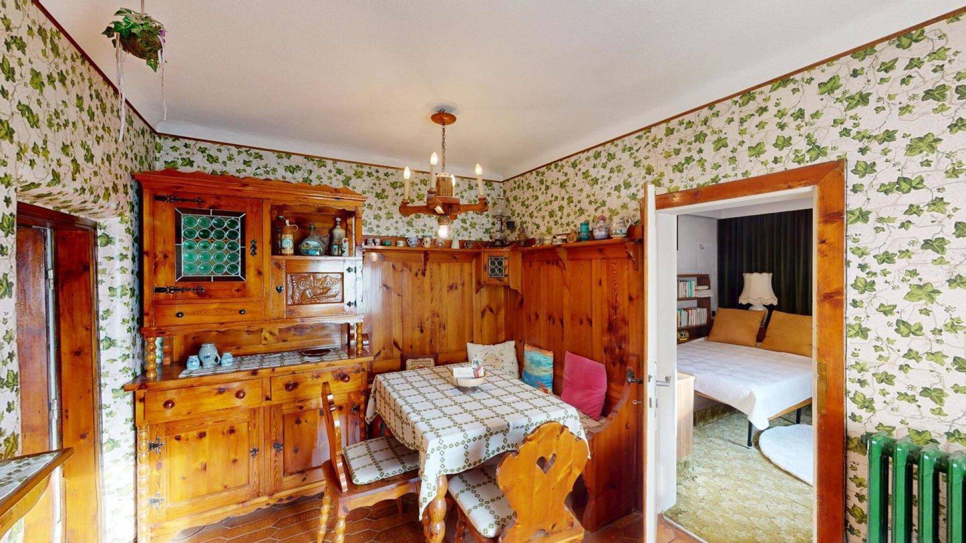 Gemütlicher Essbereich mit traditionellen Holzmöbeln, Holzvertäfelung und floraler Tapete.