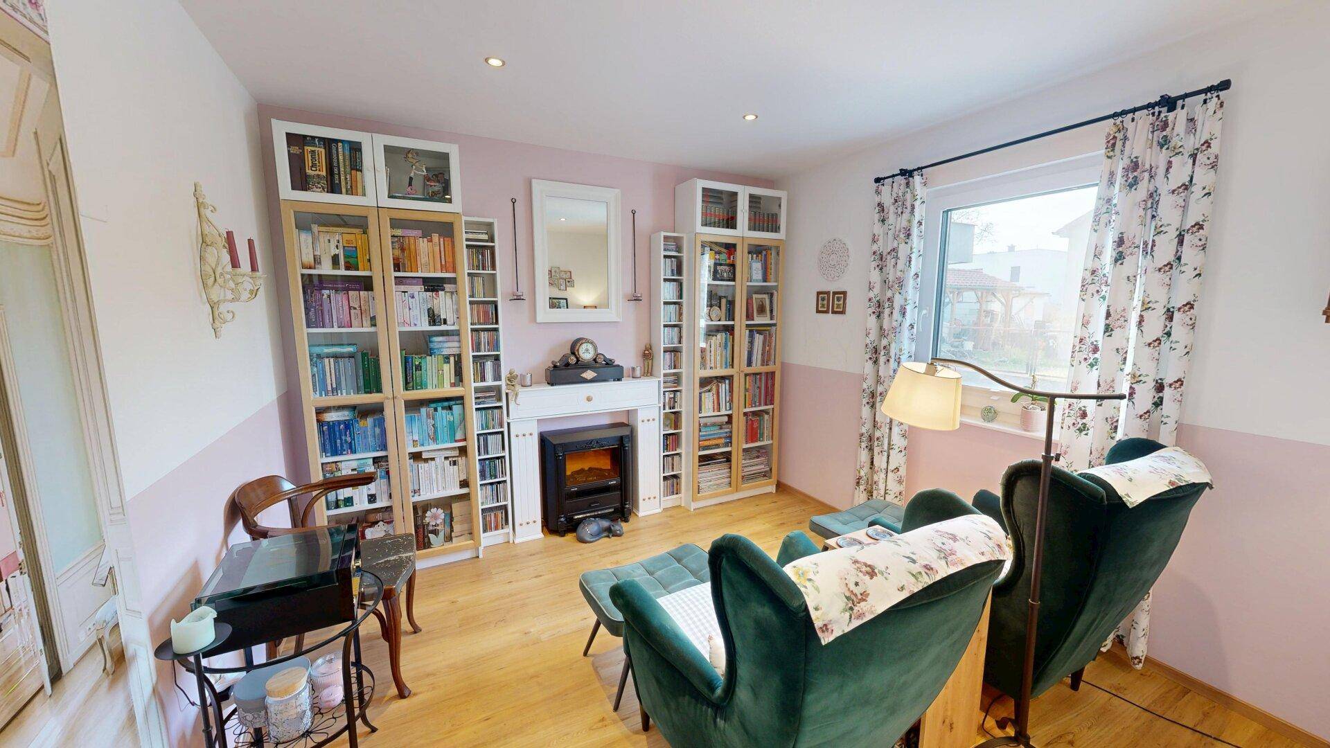 Gemütliches Wohnzimmer mit Bücherregalen, dekorativem Kamin und Holzboden.
