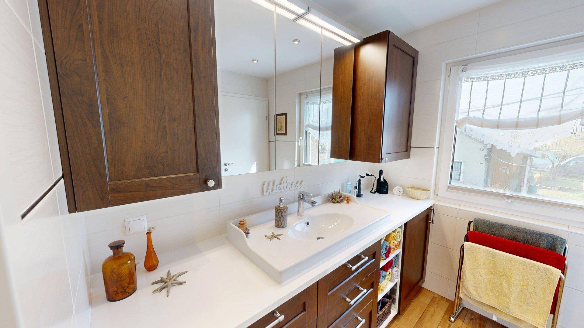 Modernes Badezimmer mit Einzelwaschbecken, Spiegelschrank und Fenster.
