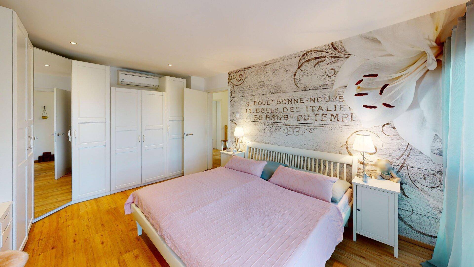 Geräumiges Schlafzimmer mit Doppelbett, Einbauschränken und dekorativer Wand.