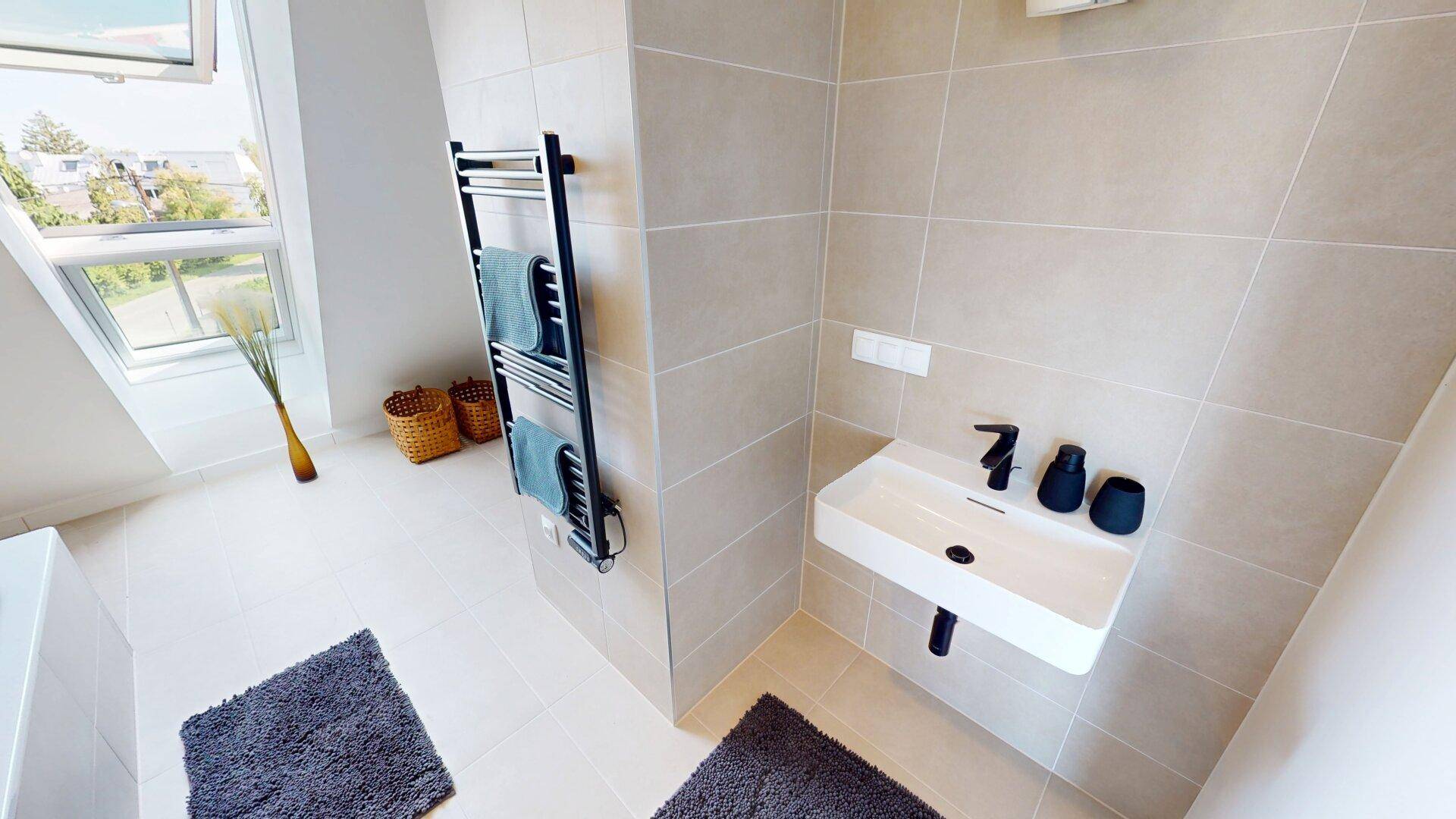 Helles Badezimmer mit modernem Waschbecken, beheiztem Handtuchhalter und Dachfenster.