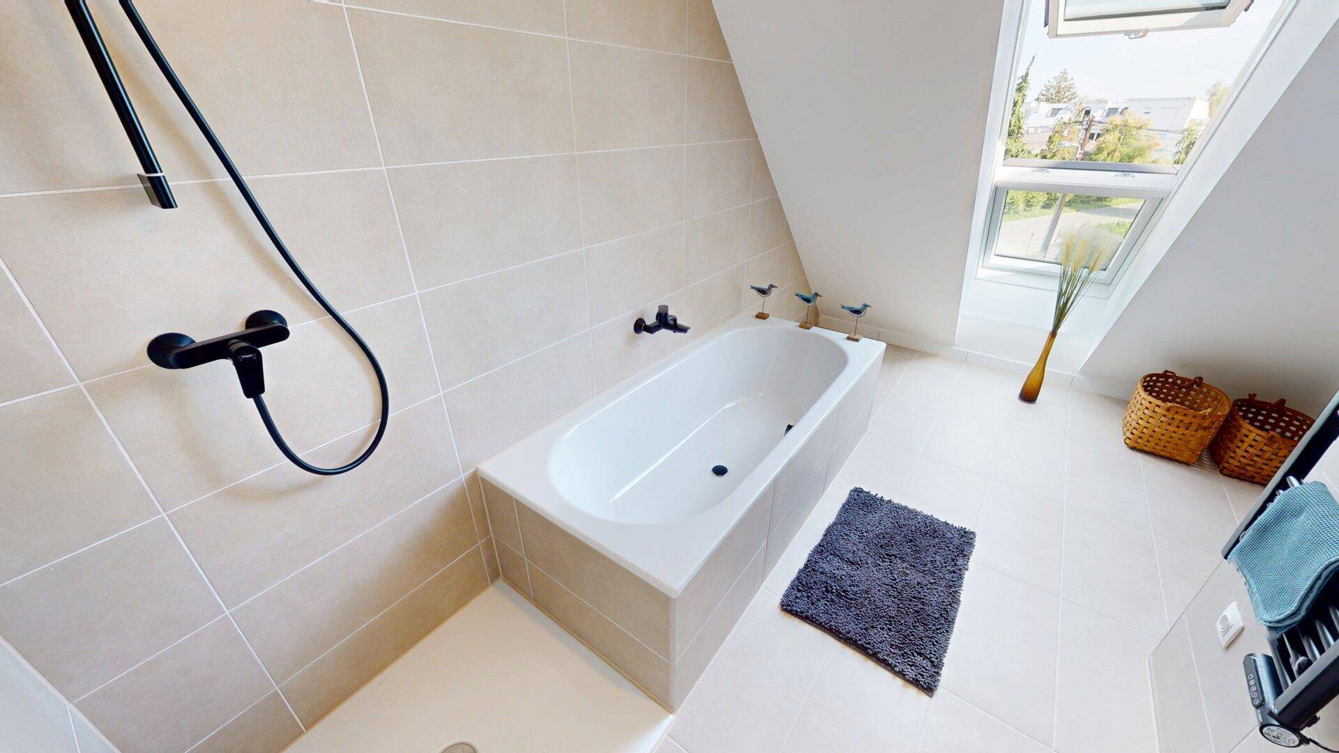 Modernes Badezimmer mit Badewanne, Dusche und Dachfenster für natürliches Licht.