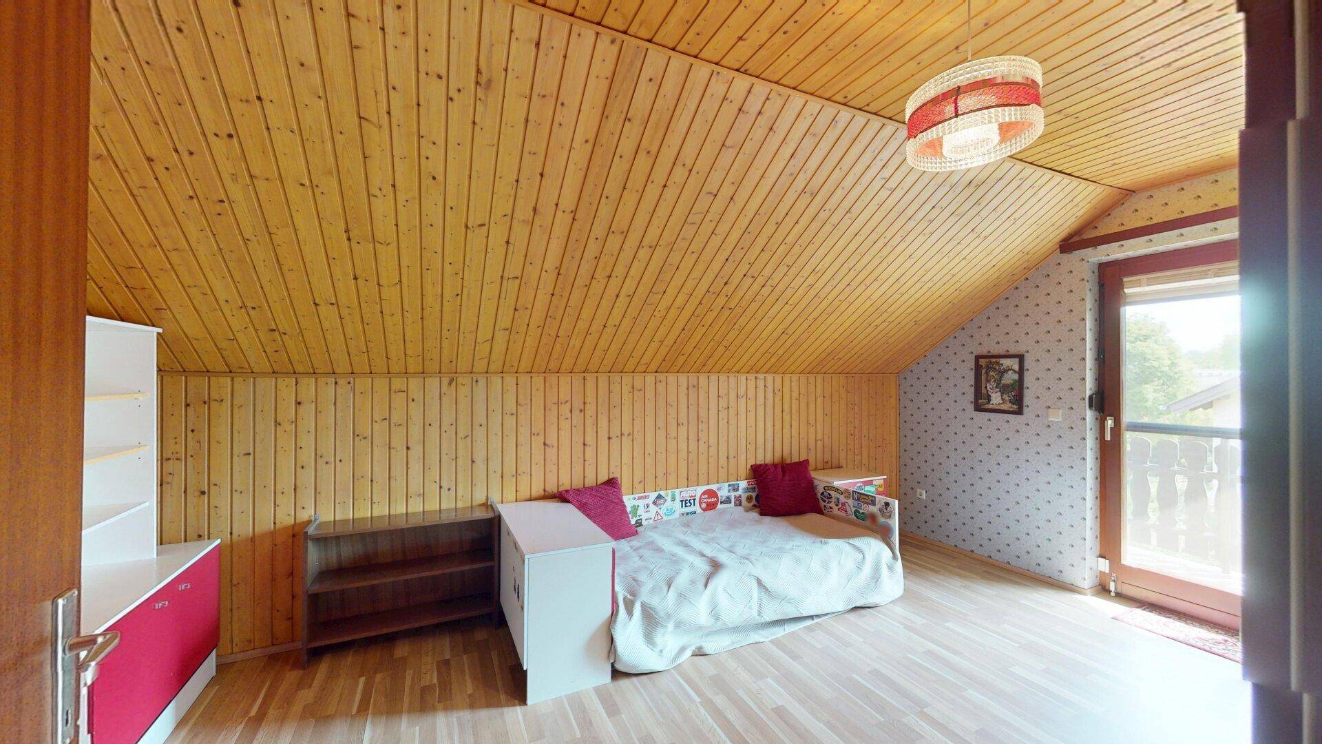 Gemütliches Dachgeschoss-Schlafzimmer mit Holzvertäfelung, Dachschräge und Balkonzugang.