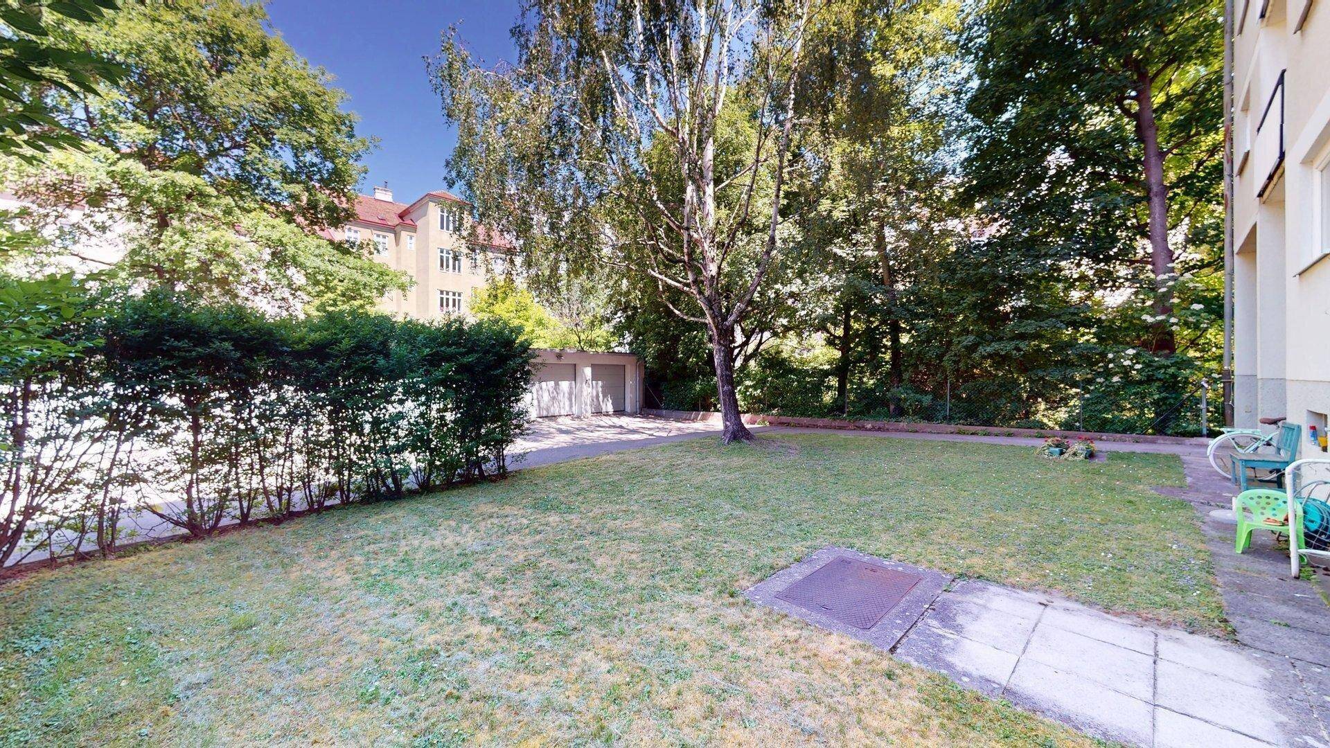 Gemeinschaftsgarten mit Rasenfläche, Bäumen und Hecke, bietet viel Grünfläche.