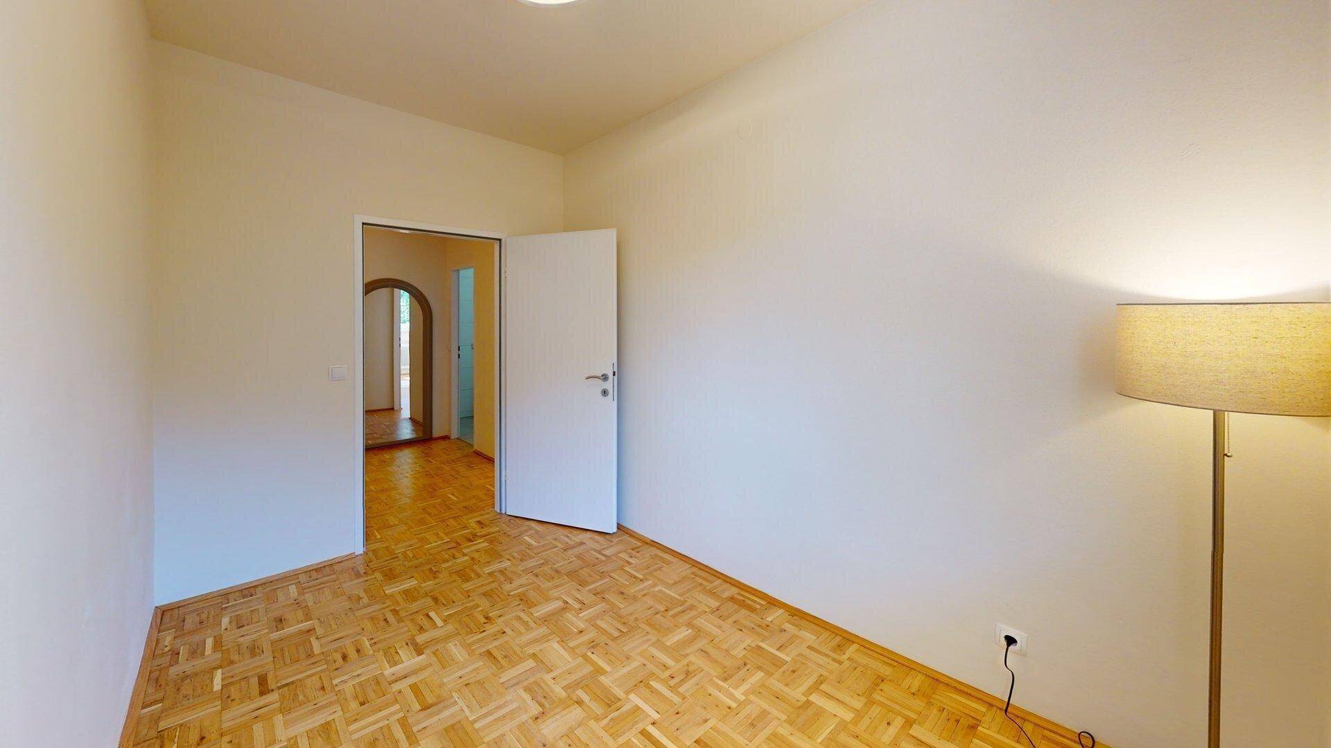 Helles Zimmer mit Parkettboden und Zugang zum Flur, vielseitig nutzbar.
