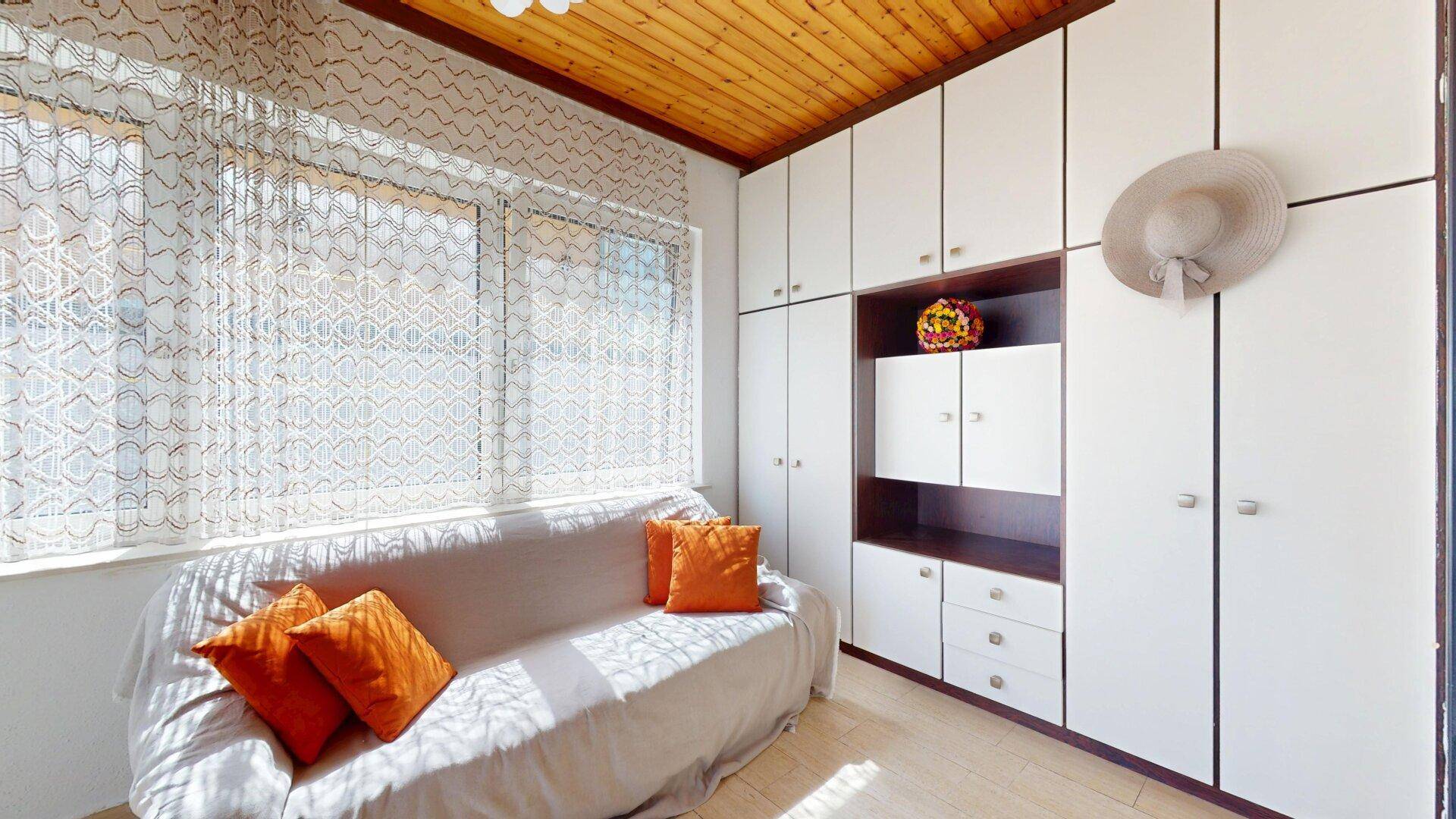 Gemütliches Zimmer mit Holzdecke, Einbauschränken und einem Schlafsofa.