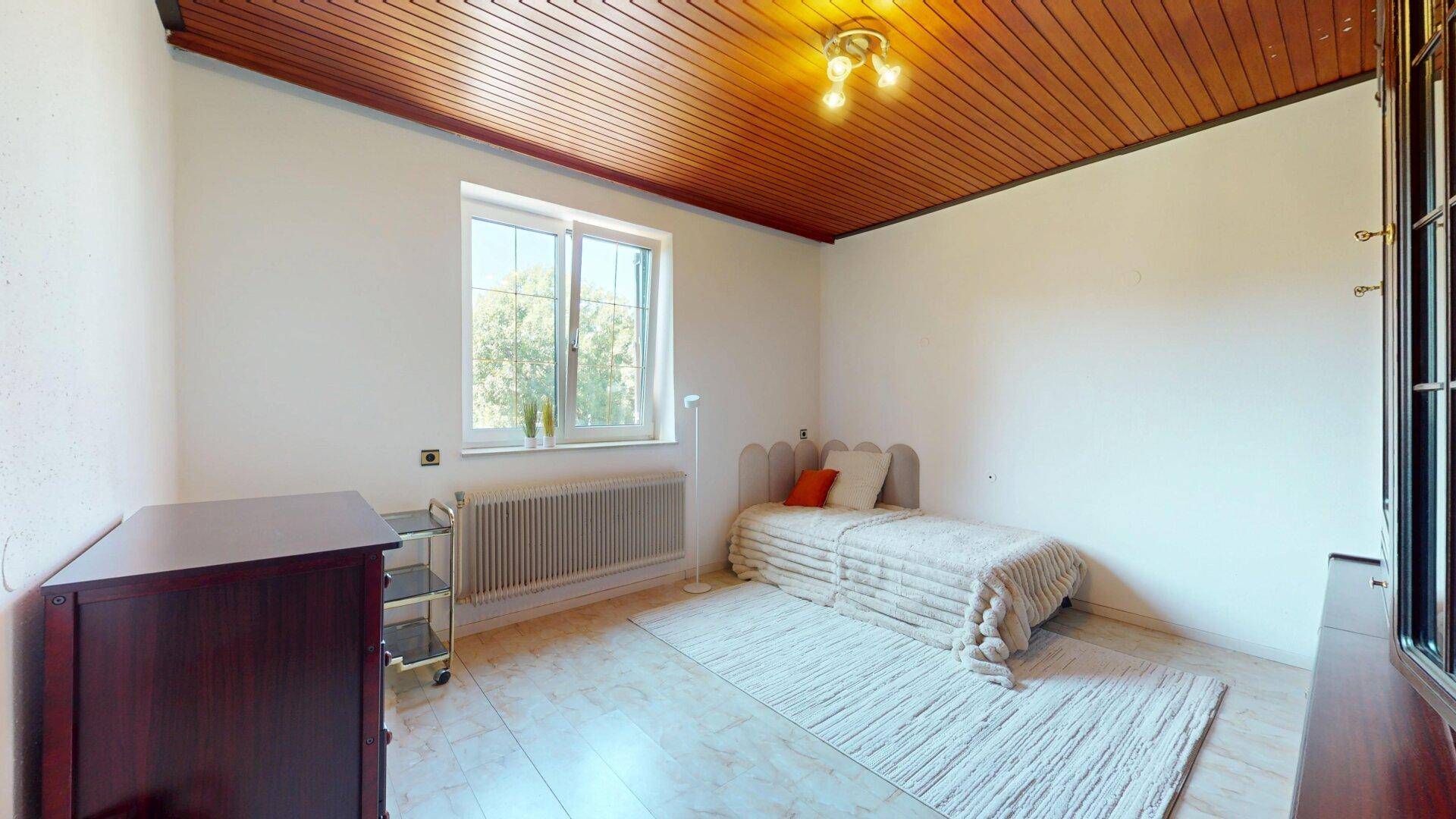 Helles Schlafzimmer mit Holzdecke, Einzelbett und Fliesenboden.