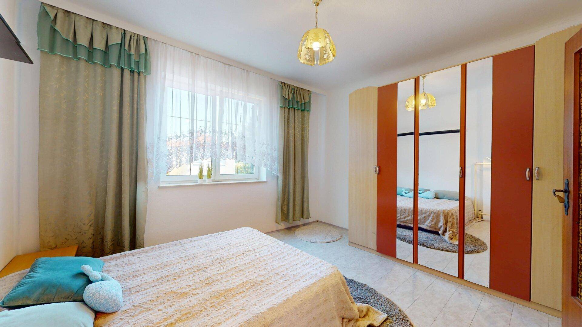 Schlafzimmer mit Doppelbett, Spiegelschränken und großem Fenster.