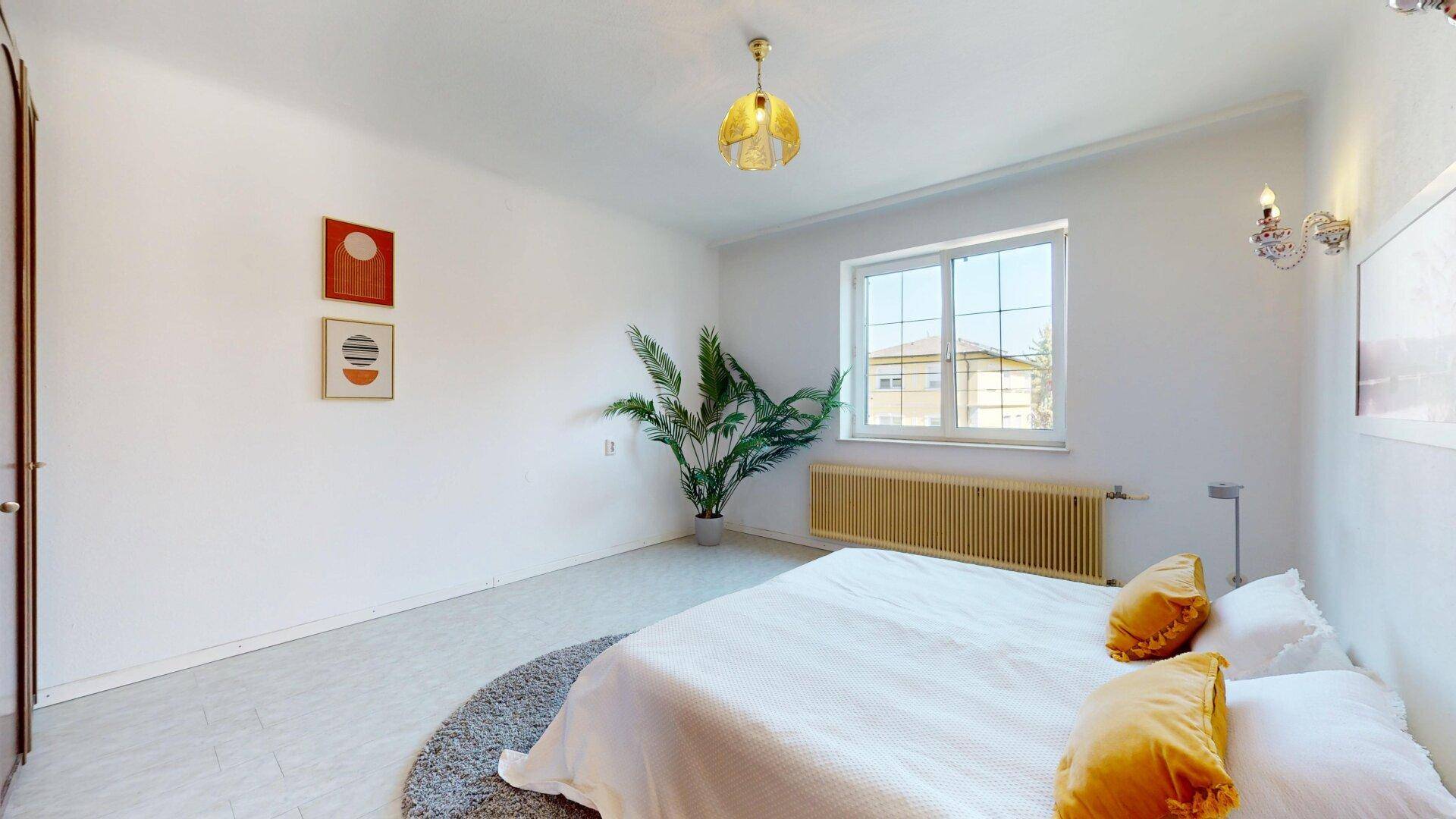 Geräumiges Schlafzimmer mit Doppelbett, Pflanzen und hellem Fliesenboden.