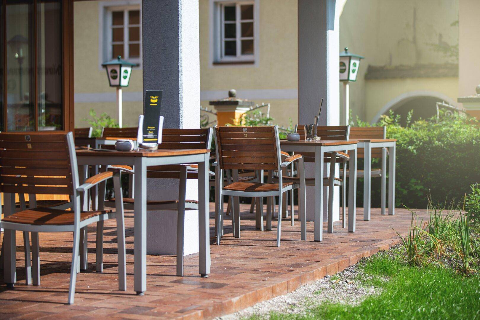 Gemütliche Außenterrasse mit Holztischen und Stühlen, ideal für entspannte Stunden im Freien.