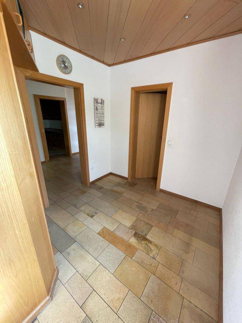 Ecke eines Flurs mit Fliesenboden und Holztüren, die zu weiteren Räumen führen.