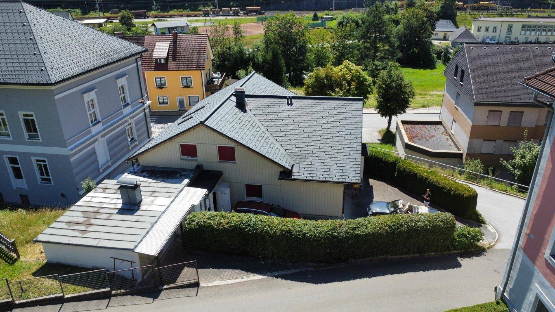 Luftaufnahme des Hauses mit umliegenden Gebäuden, Straßen und weitreichender grüner Landschaft.