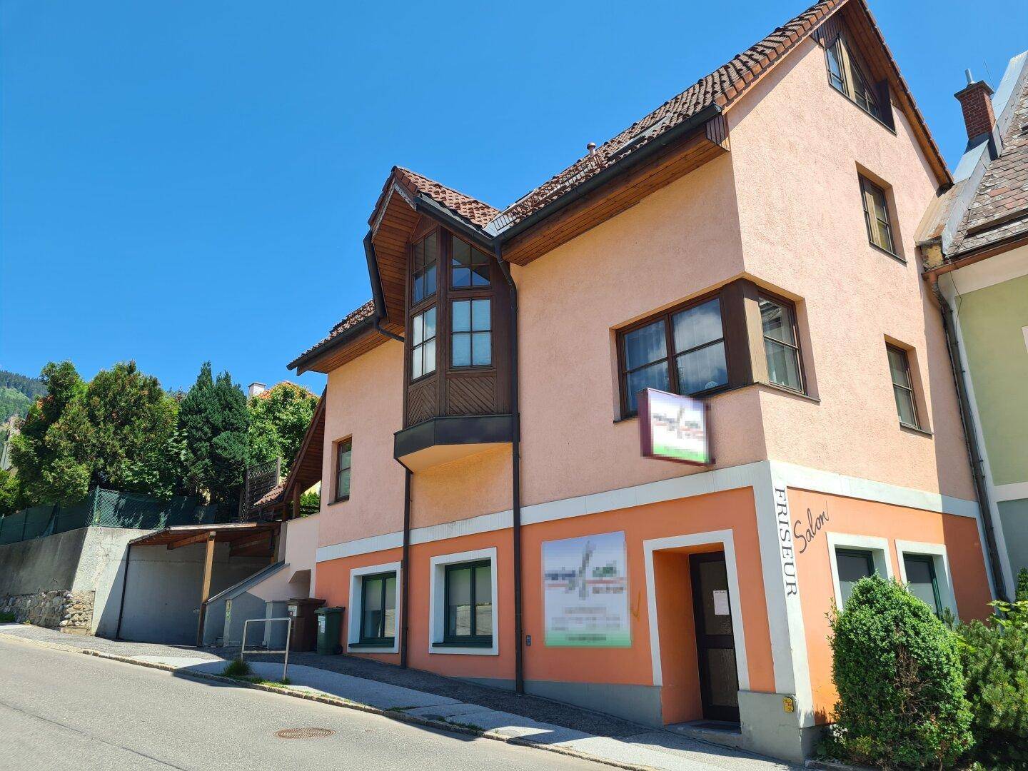 Ansicht der Hausfassade von der Straße mit Erkerfenster und einem Friseursalon im Erdgeschoss.