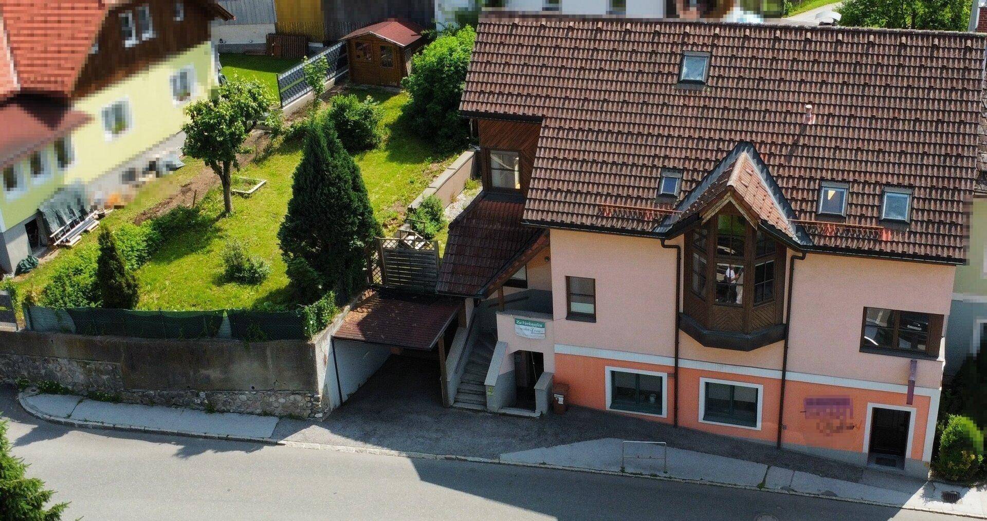 Ansicht des Hauses von oben mit der Straßenseite, Carport und dem angrenzenden Grundstück.