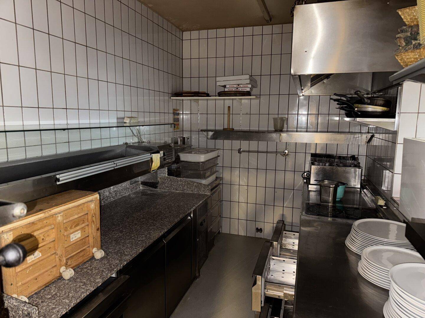 Professionelle Küche mit Edelstahlgeräten, gefliesten Wänden und Arbeitsflächen aus Granit.