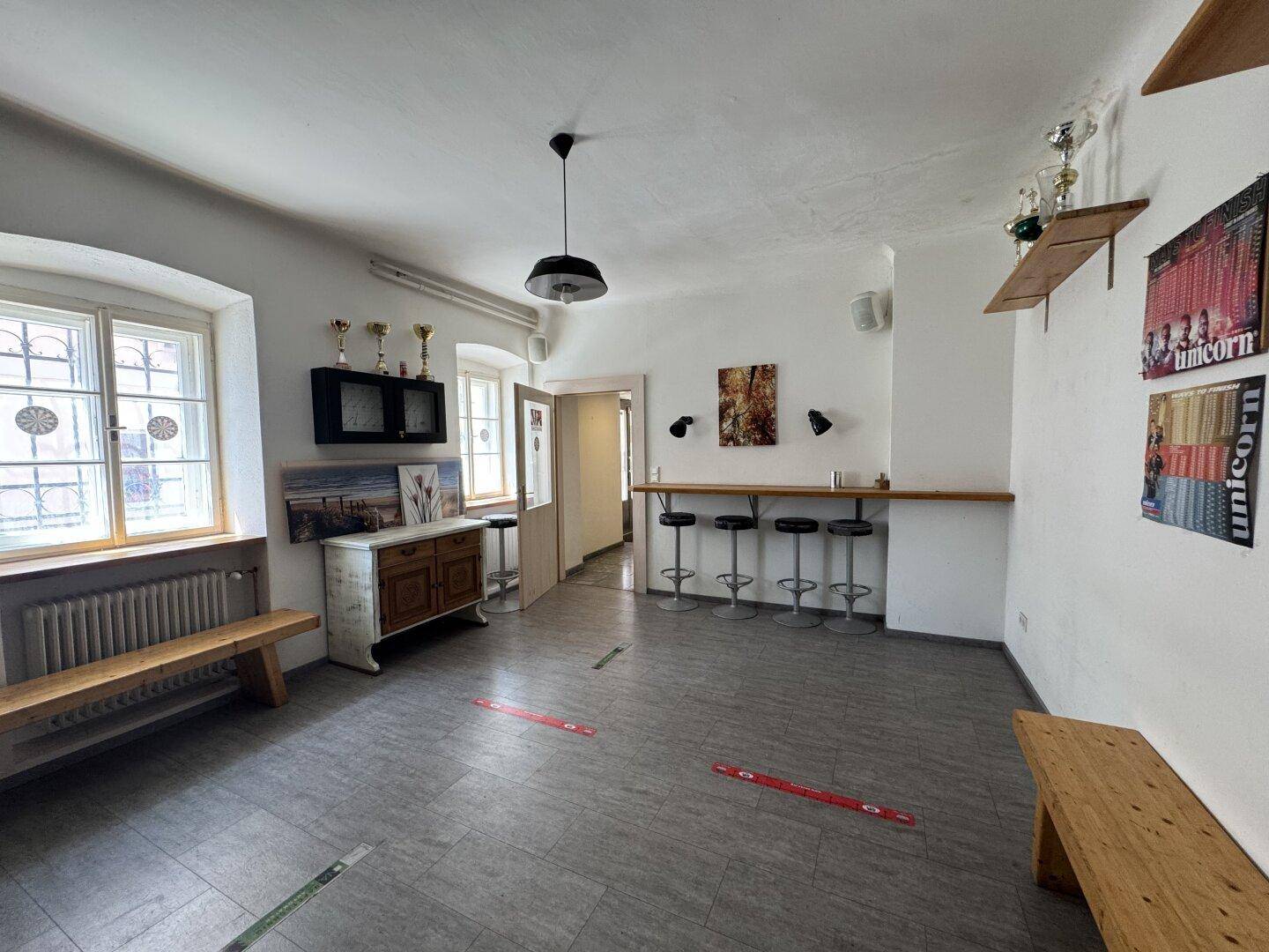 Geräumiger Flur mit Fliesenboden, Sitzbänken und einer Bar mit Hockern.