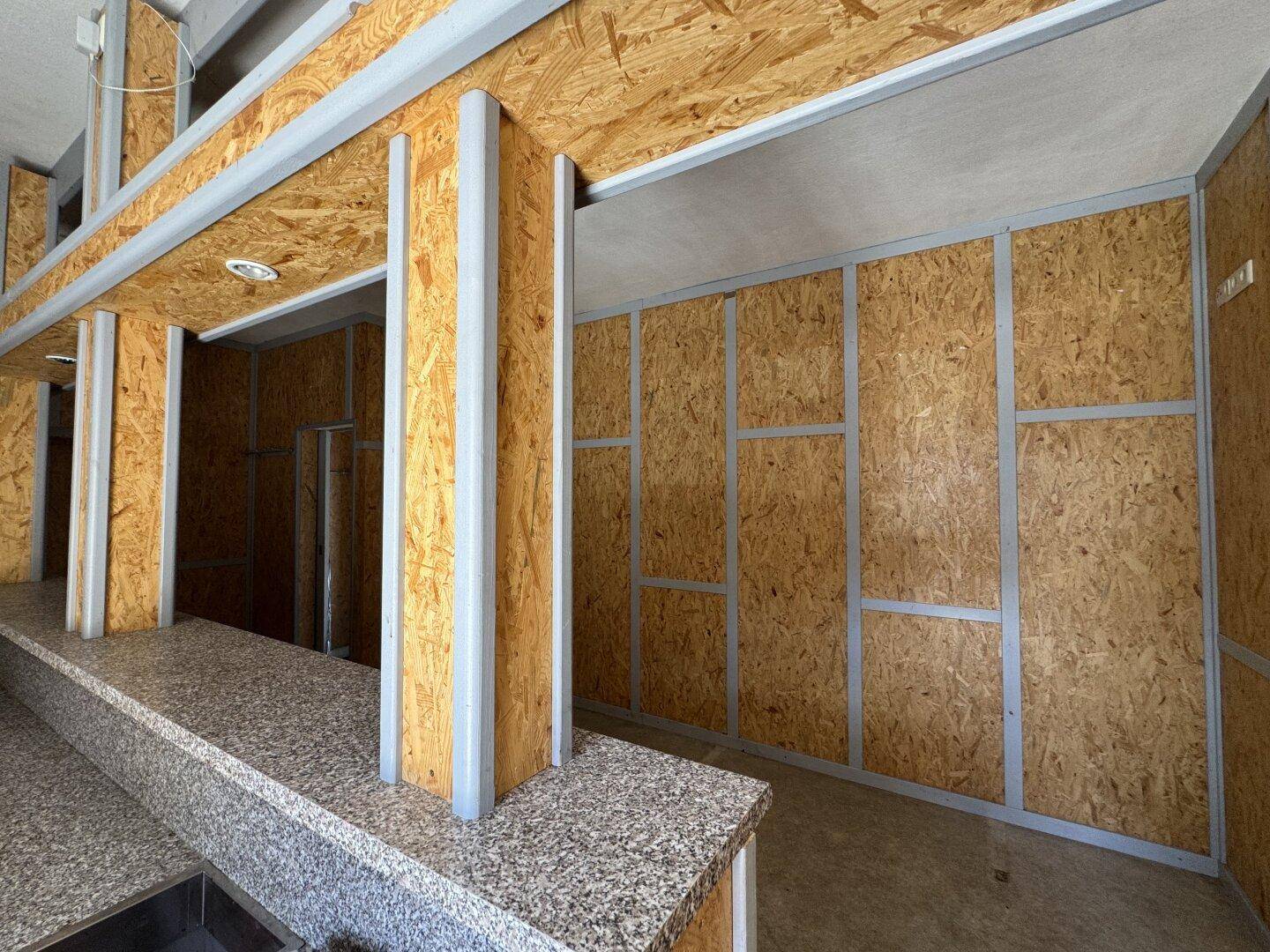 Unfertiger Raum mit OSB-Plattenwänden und Granit-Arbeitsflächen, möglicherweise eine zukünftige Bar.