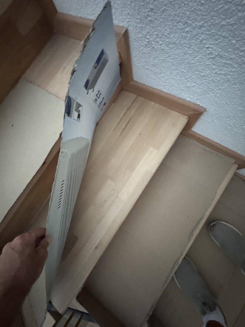 Detailansicht der Holztreppe mit Schutzabdeckung während der Renovierungsarbeiten.