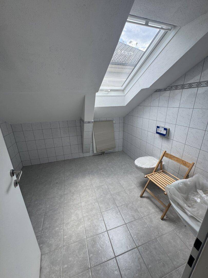 Badezimmer im Dachgeschoss mit Fliesenboden, Dachfenster und vorbereiteten Anschlüssen.