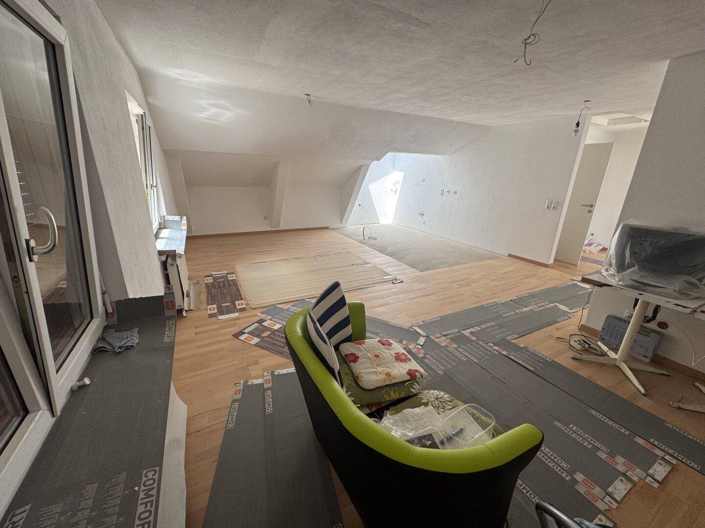 Geräumiger Wohnbereich im Dachgeschoss mit Holzboden und viel Tageslicht.