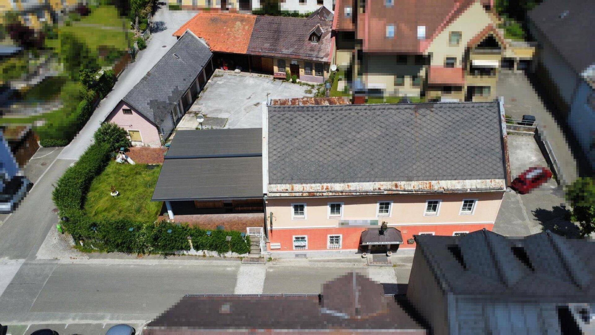 Draufsicht auf das Anwesen mit großem Parkplatz, angrenzendem Grünbereich und umliegenden Gebäuden.