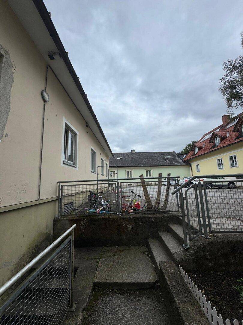 Außenansicht des Gebäudes mit Metallgeländer und Treppenabgang zu einem unteren Bereich.
