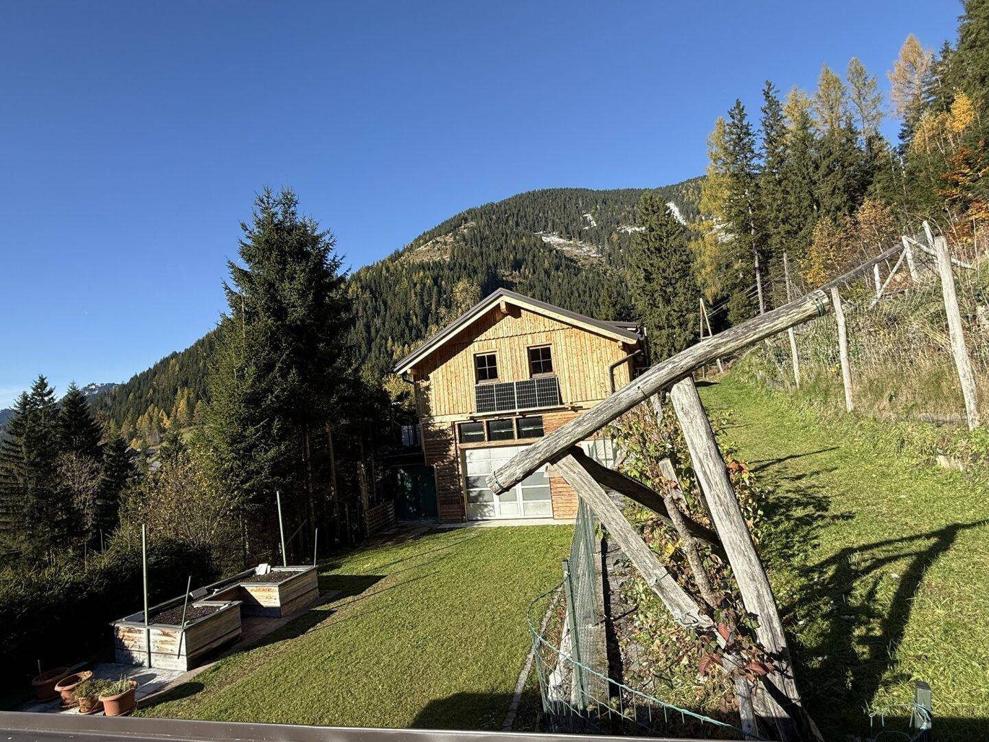 Charmantes Holzhaus in Hanglage mit Photovoltaikanlage und weitem Blick auf die Berge.