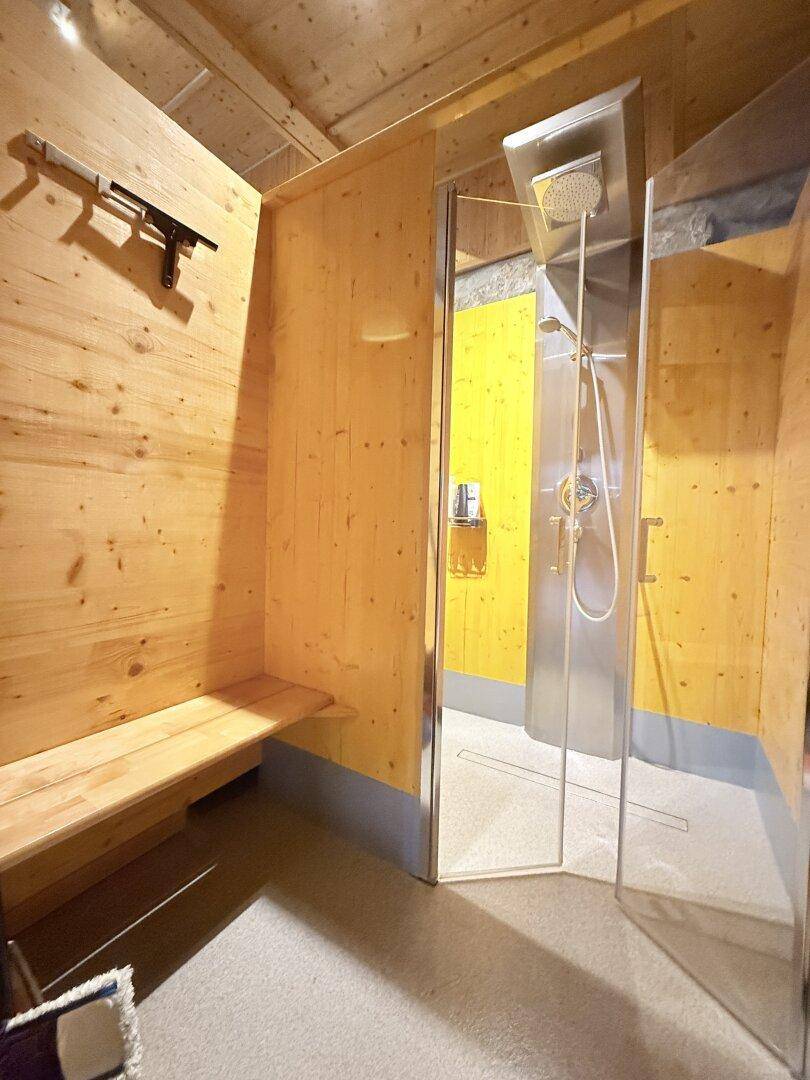 Moderne Duschkabine mit Holzverkleidung im Wellnessbereich, ideal nach dem Schwimmen.